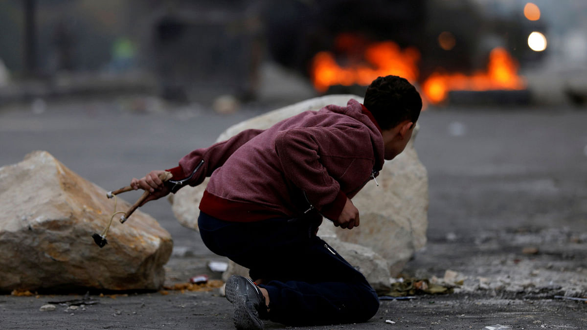 A Palestinian demonstrator takes cover during clashes with Israeli troops, at a protest as Palestinians call for a `Day of Rage` in response to US president Donald Trump`s recognition of Jerusalem as Israel`s capital, near the West Bank city of Nablus, 22 December 2017. Reuters