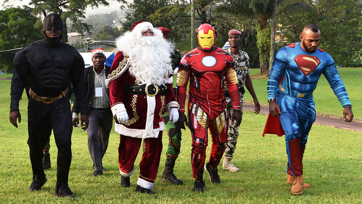 People dressed as (L-R) Batman, Santa Claus, Iron Man and Superman walk at the Presidential Palace in Abidjan on 23 December .Photo: AFP