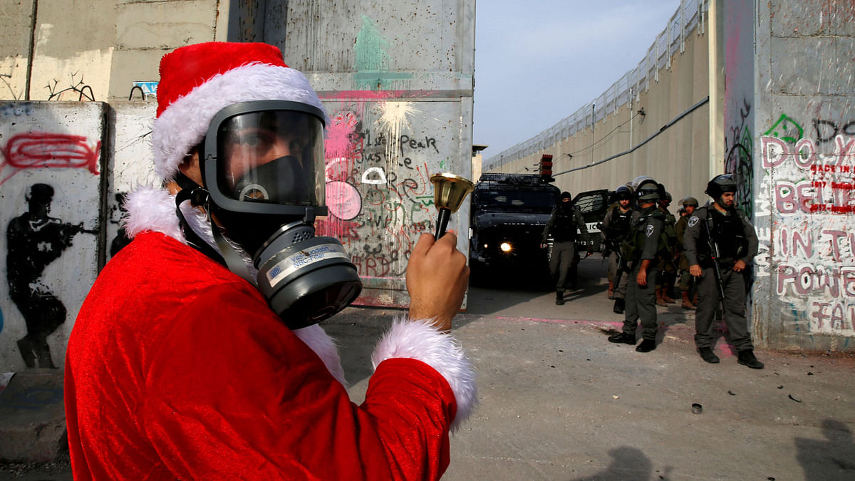 A Palestinian dressed as Santa Claus stands in front of Israeli troops during a protest in the West Bank city of Bethlehem on 23 December. Photo: Reuters