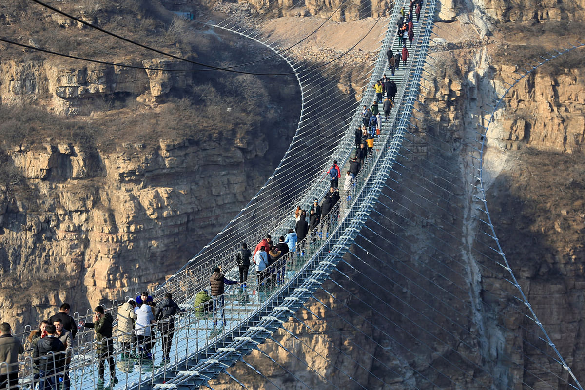 Visitors walk on the newly opened 488-metre-long glass suspension bridge at Pingshan in China on 26 December 2017. Photo: Reuters