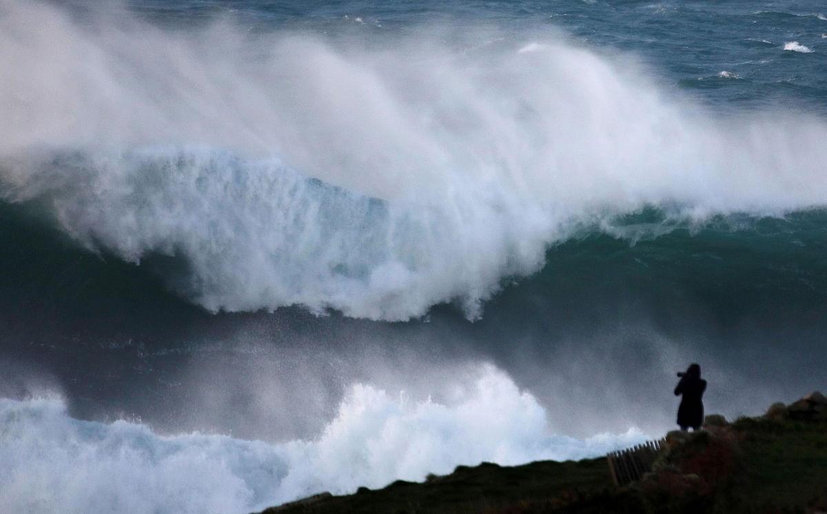 A photographer takes pictures of waves breaking on the Brittany coast at Audierne in western France