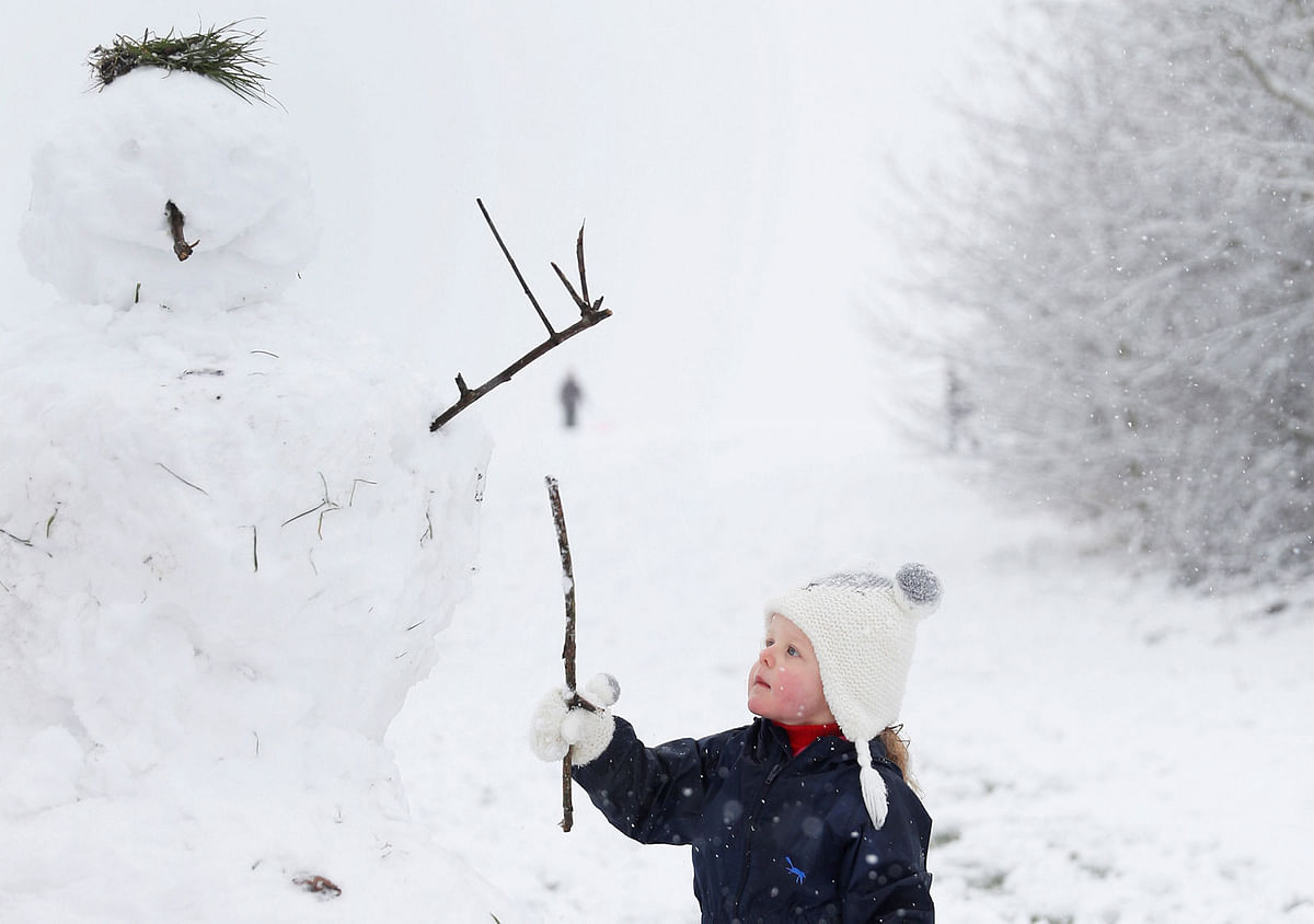 A girl plays with a snowman in Ouston, County Durham, Britain, on 29 December 2017. Photo: Reuters