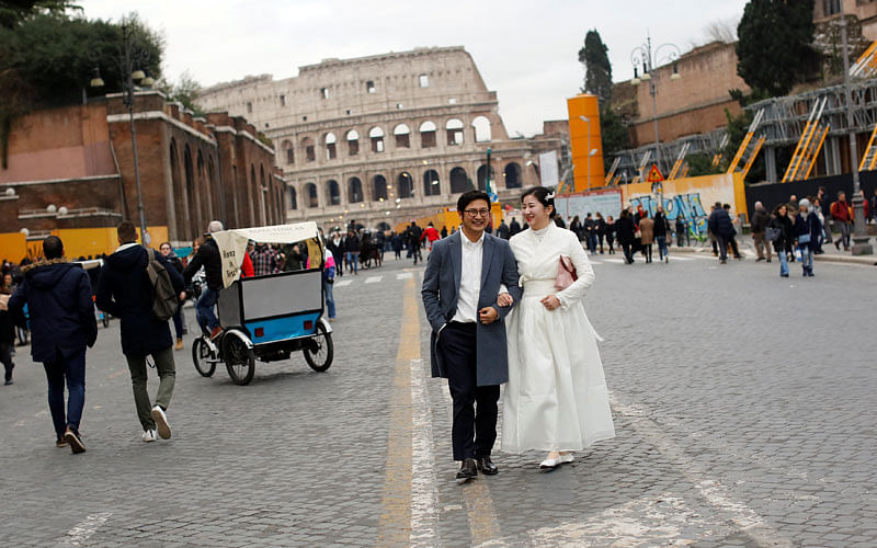 A newly-wed couple walk near the Colosseum in Rome, Italy on 30 December 2017. Photo: Reuters