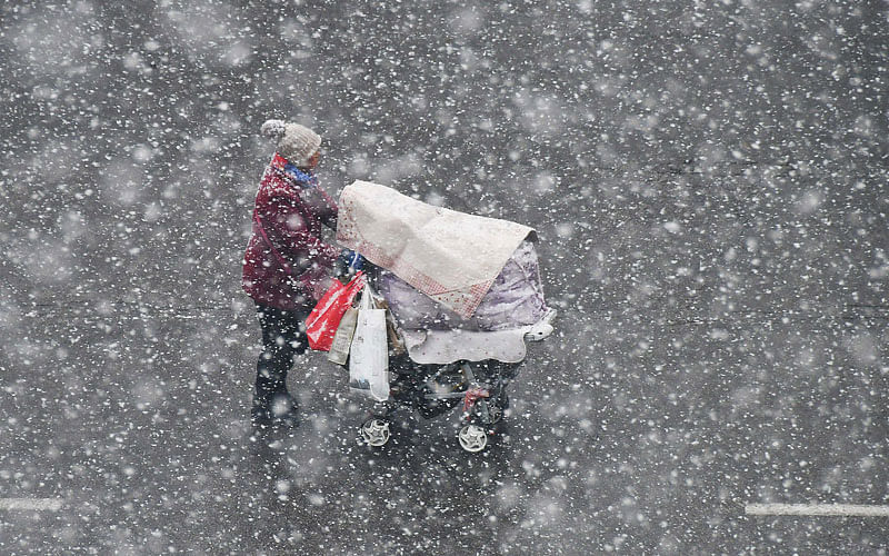 A woman pushing a stroller walks in the snow in Yantai, Shandong province, China on 4 December 2017. Photo: Reuters