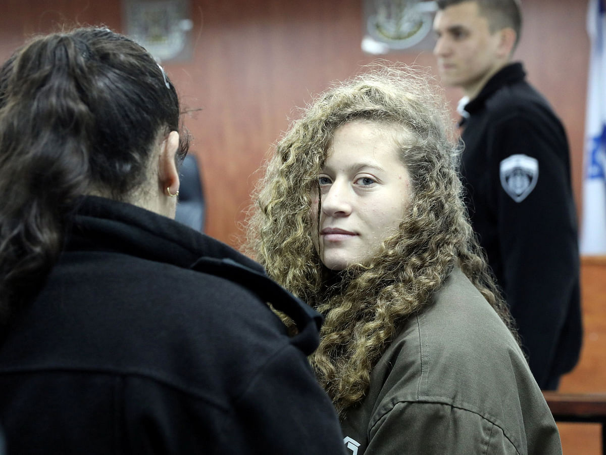 Palestinian teen Ahed Tamimi (R) enters a military courtroom escorted by Israeli Prison Service personnel at Ofer Prison, near the West Bank city of Ramallah on 1 January 2018. Photo: Reuters