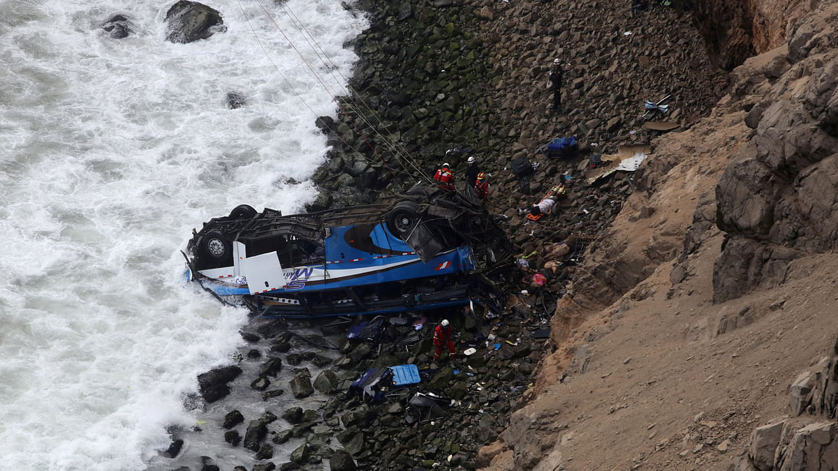 Rescue workers stand at the scene after a bus crashed with a truck and careened off a cliff along a sharply curving highway north of Lima, Peru on 2 January. Photo: Reuters