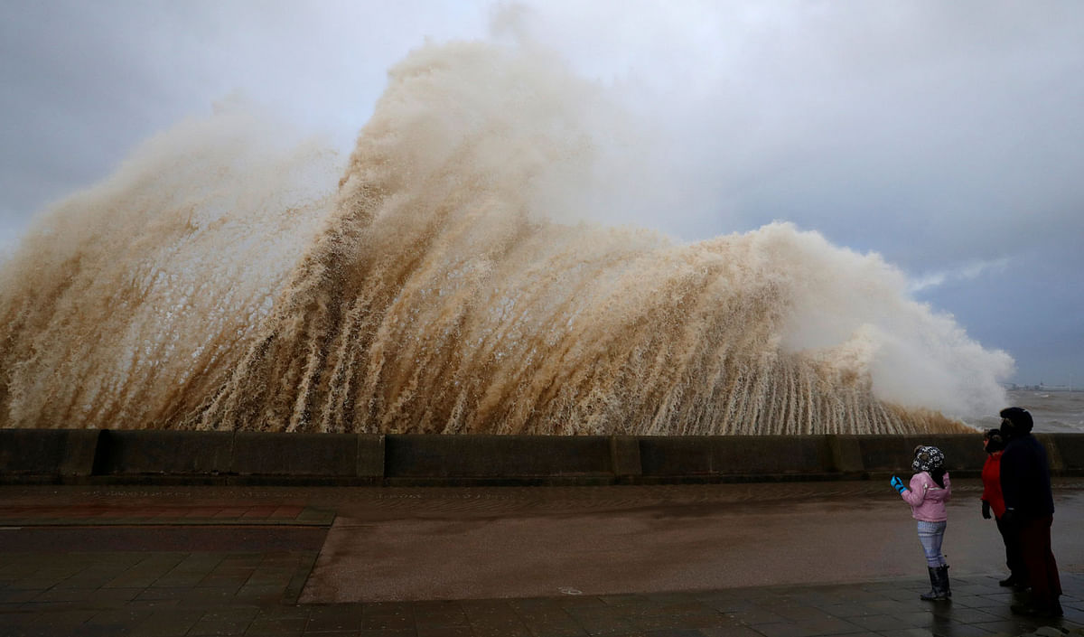 Walkers watch the waves breaking in New Brighton, on the coast of the Wirral peninsula, in Merseyside, Britain, on 3 January 2018. Photo: Reuters