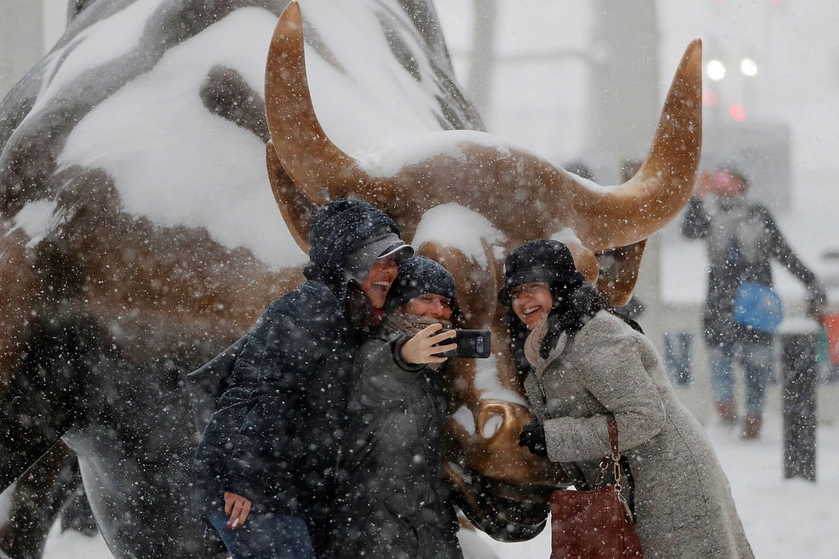 Tourists pose with the charging bull statue during Storm Grayson in New York, US, 4 January 2018. Photo: Reuters