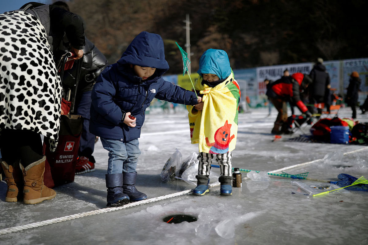 Children fish for trout on a frozen river during the Ice Festival in Hwacheon, South Korea on 6 January 2018. Photo: Reuters