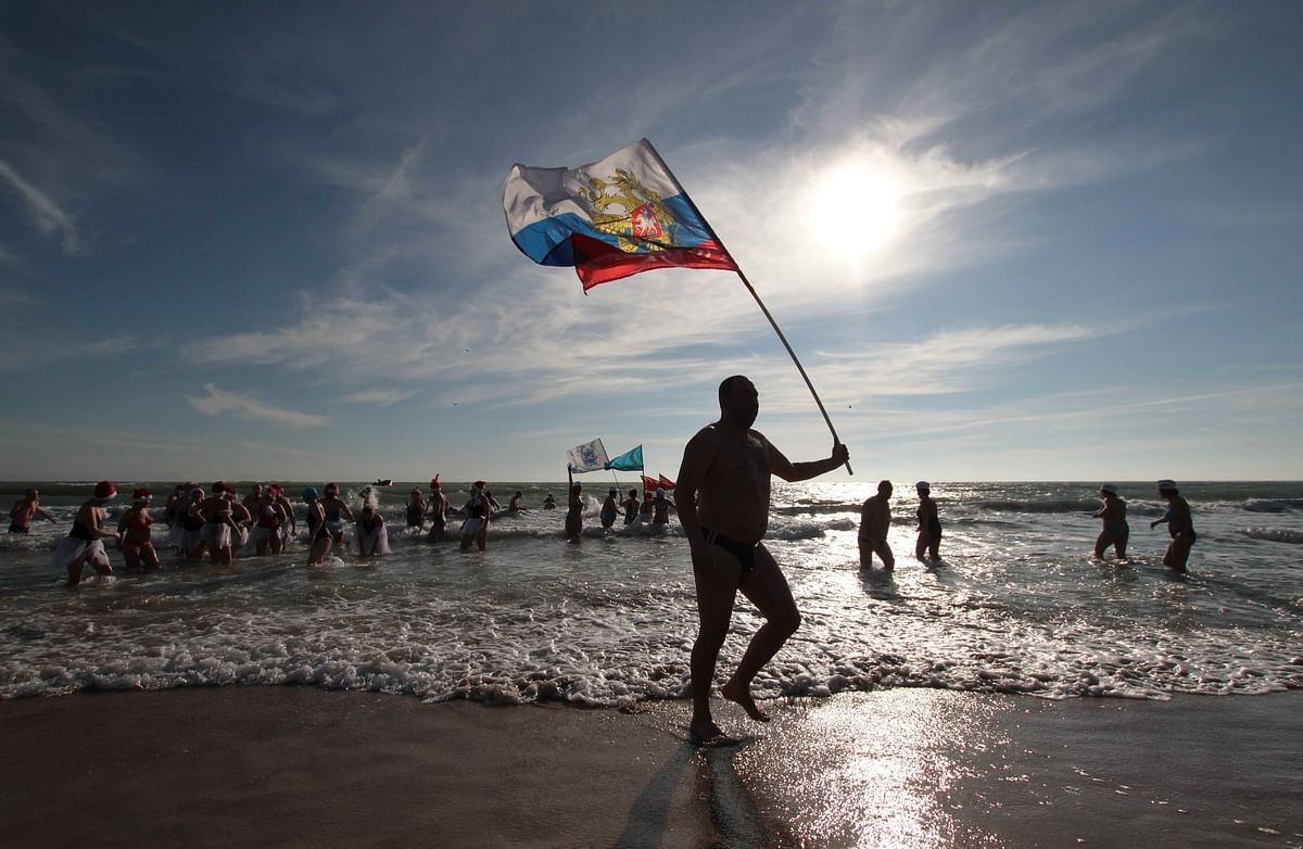 A fan of winter swimming holds the Russian national flag during an event, marking Orthodox Christmas, in the Black Sea port of Yevpatoriya, Crimea on 7 January 2018. Reuters