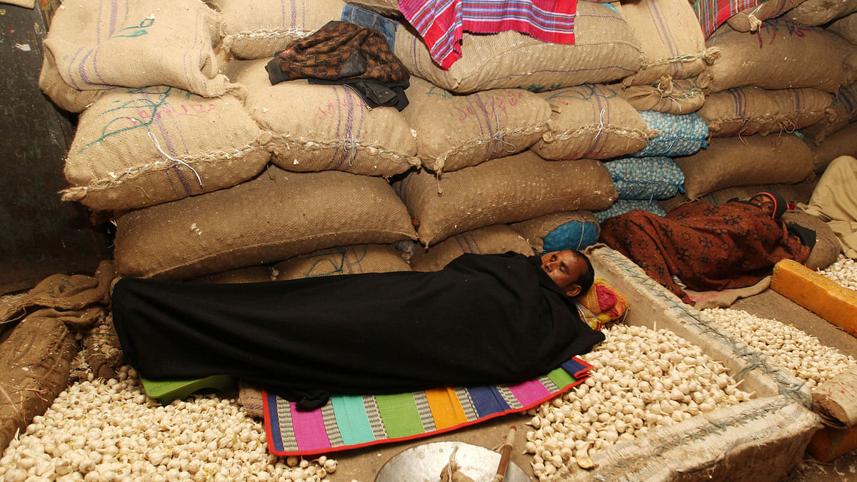 A vendor sleeps covering himself with a blanket at Karwan Bazar on 8 January. Photo: Sajid Hossain