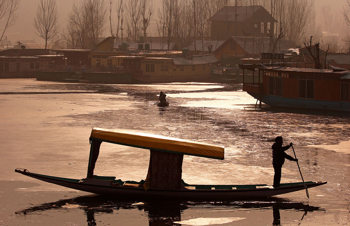 A man rows his boat on partially frozen interiors of the Dal Lake on a cold winter morning in Srinagar
