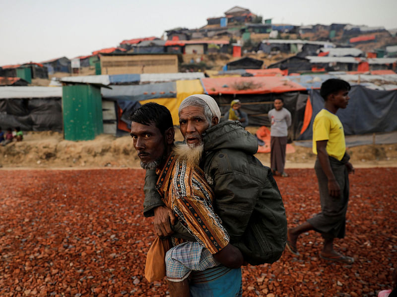 Rohingya refugee carries an elderly man at the Palongkhali refugee camp near Cox`s Bazar. Reuters file photo