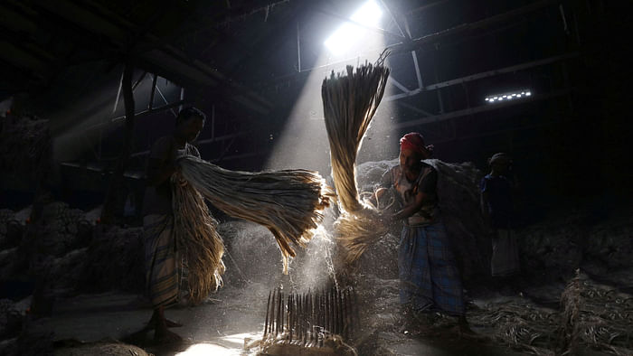 Sunrays enter through the rooftop as employees work at a jute processing mill in Narayanganj