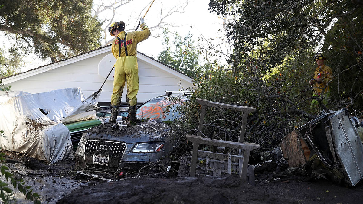 A fire fighter looks through a car next to a home that was destroyed by a mudslide on 12 January 2018 in Montecito, California. Photo: AFP