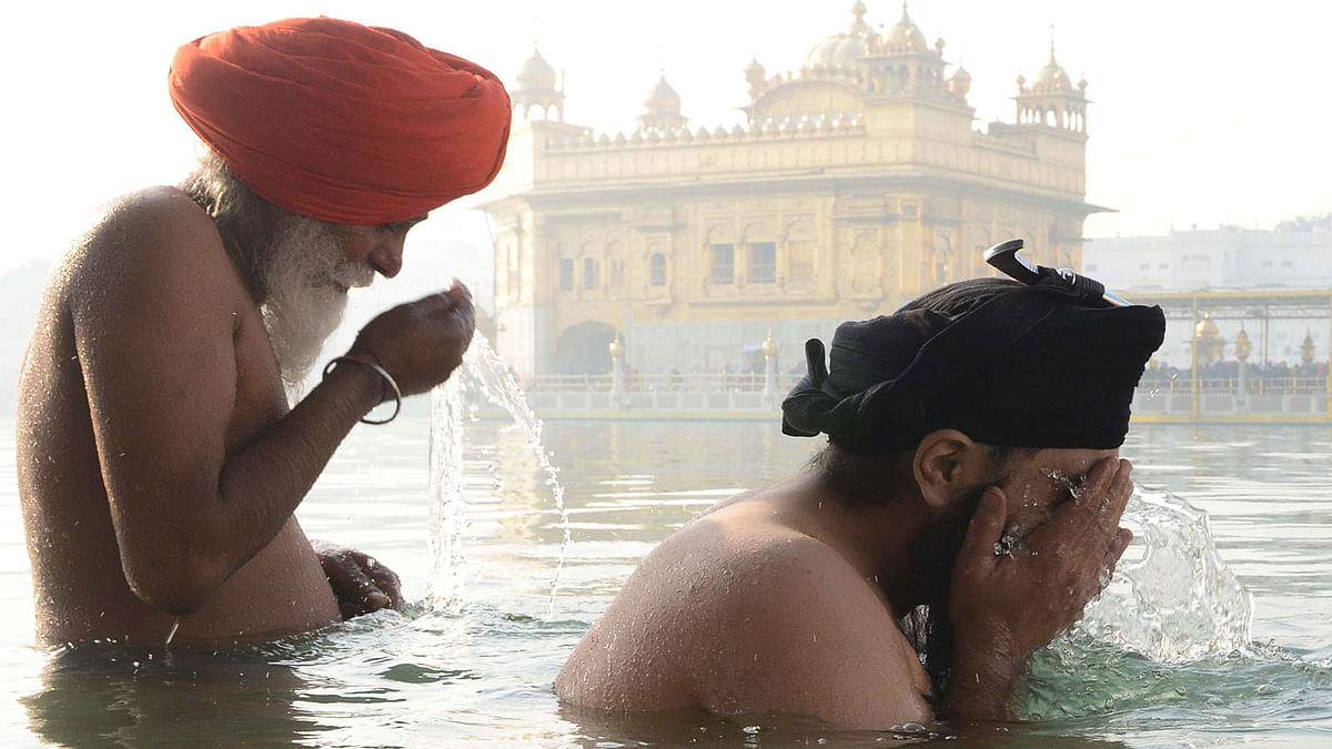 Indian Sikh devotees take a dip in the holy sarovar (water tank) during the Magh Mela at the Golden Temple in Amritsar on 14 January 2018. Photo: AFP