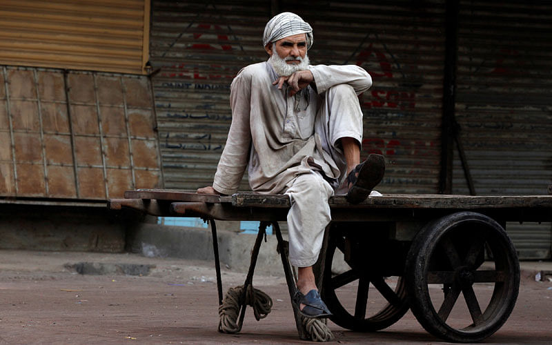 A laborer sits on a pushcart while waiting for work at a wholesale market early morning in Karachi, Pakistan on 16 January. Photo: Reuters