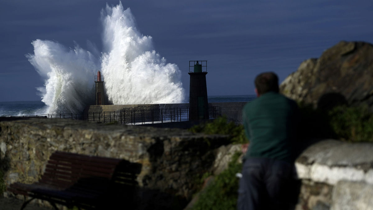 A man looks at waves as they crash against a lighthouse in the port town of Viavelez, Spain, 18 January 2018. Photo: Reuters