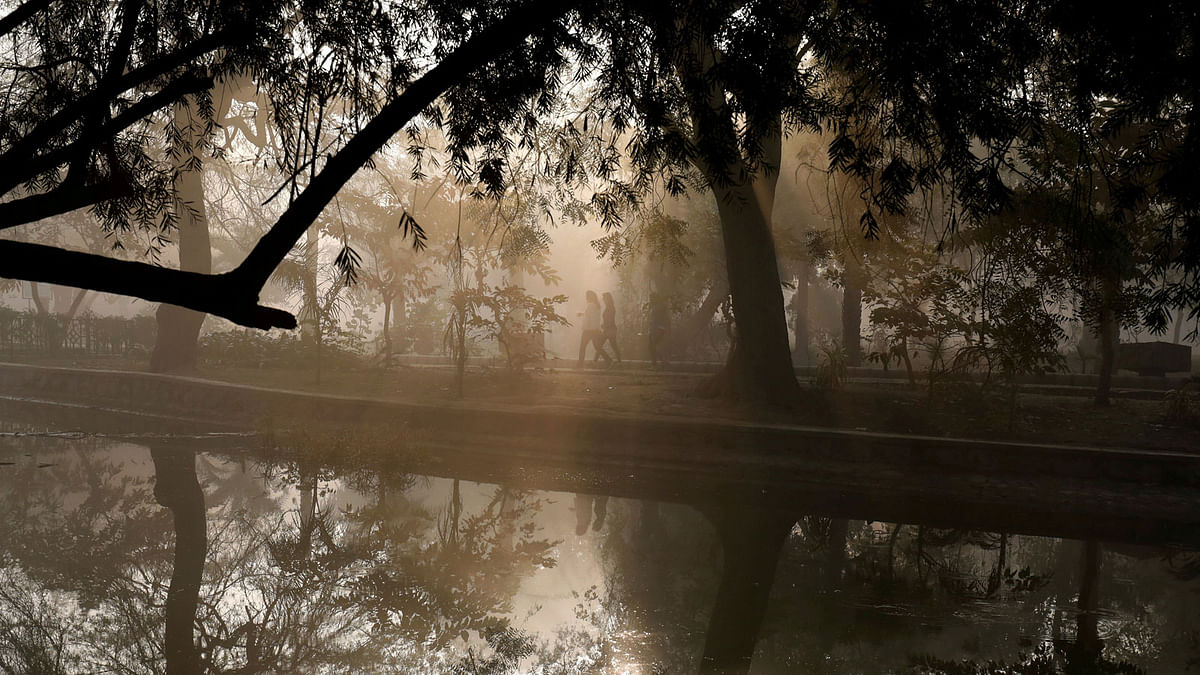 People walk by a lake at a public park on a foggy winter morning in New Delhi, India 19 January 2018. Photo: Reuters