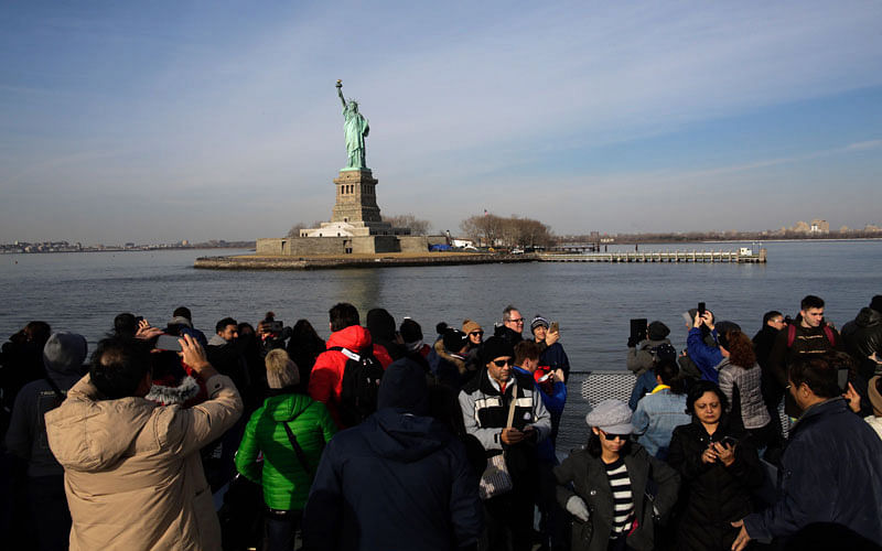 People take pictures as they to go around the Statue of Liberty on January 21, 2018 in New York City. The iconic landmark remains closed as part of the US government shutdown now entering its second full day after coming into effect at midnight on Friday after senators failed to pass a new federal spending bill. AFP