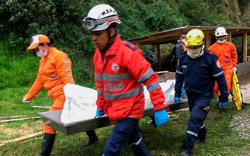 This handout picture released courtesy of Colombia`s Firefighters press office shows firefighters carrying the corpse of one of the passengers of a bus that was buried by a landslide on the road between the municipalities of Junin and Tuquerres, department of Narino, southwest of Colombia, on 21 January, 2018. Photo: AFP