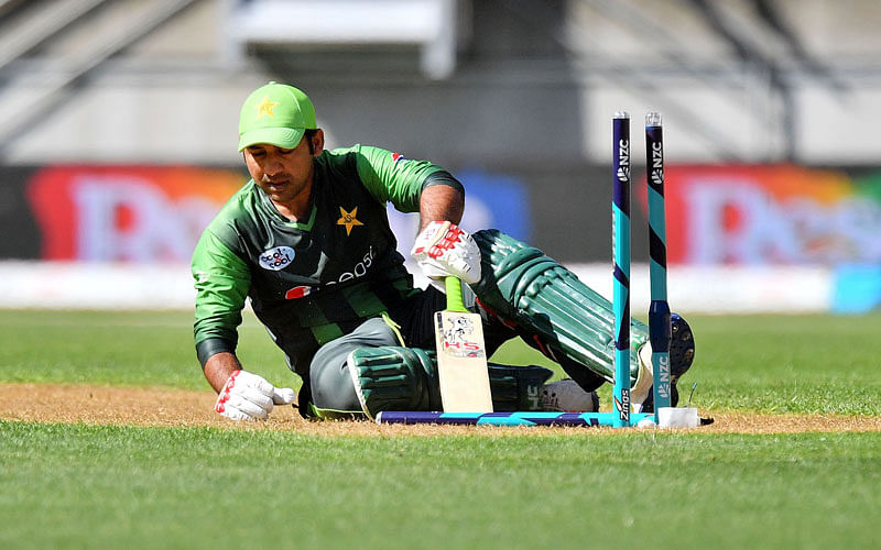 Pakistan`s Sarfraz Ahmed (C) reacts after being stumped by New Zealand`s keeper Glenn Phillips (R) watched by Mitchell Santner (L) during the first Twenty20 international cricket match between New Zealand and Pakistan at Westpac Stadium in Wellington on 22  January, 2018. Photo: AFP