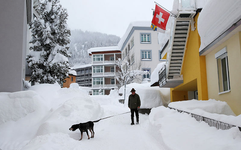 A man walks his dog after a snowfall ahead of the World Economic Forum (WEF) annual meeting in the Swiss Alps resort of Davos, Switzerland on 22 January. Photo: Reuters