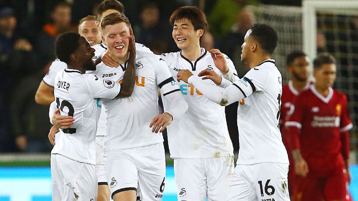 Swansea City’s English defender Alfie Mawson © celebrates with teammates after scoring the opening goal of the English Premier League football match between Swansea City and Liverpool at The Liberty Stadium in Swansea, south Wales on Monday. Photo: AFP