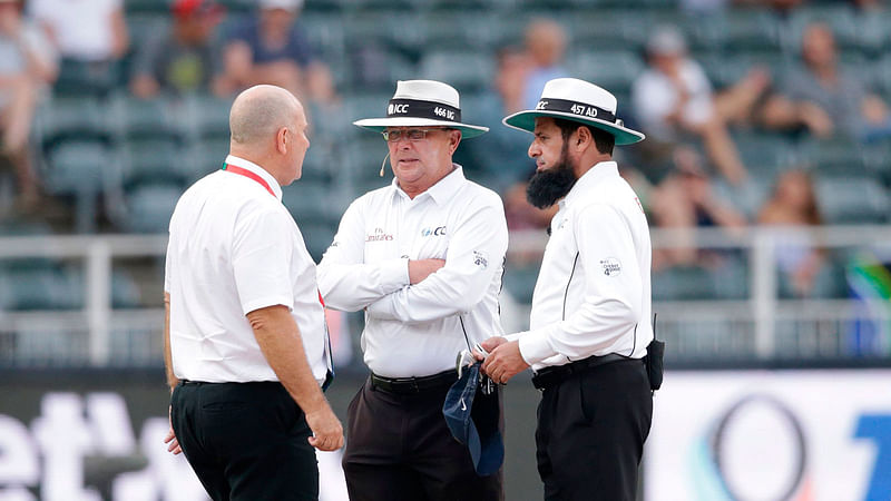 Umpires Ian Gould (C) Aleem Dar (R) and referee Andy Pycroft discuss ahead of suspending the match during the third day of the third test match between South Africa and India at Wanderers cricket ground on 26 January 2018 in Johannesburg. AFP