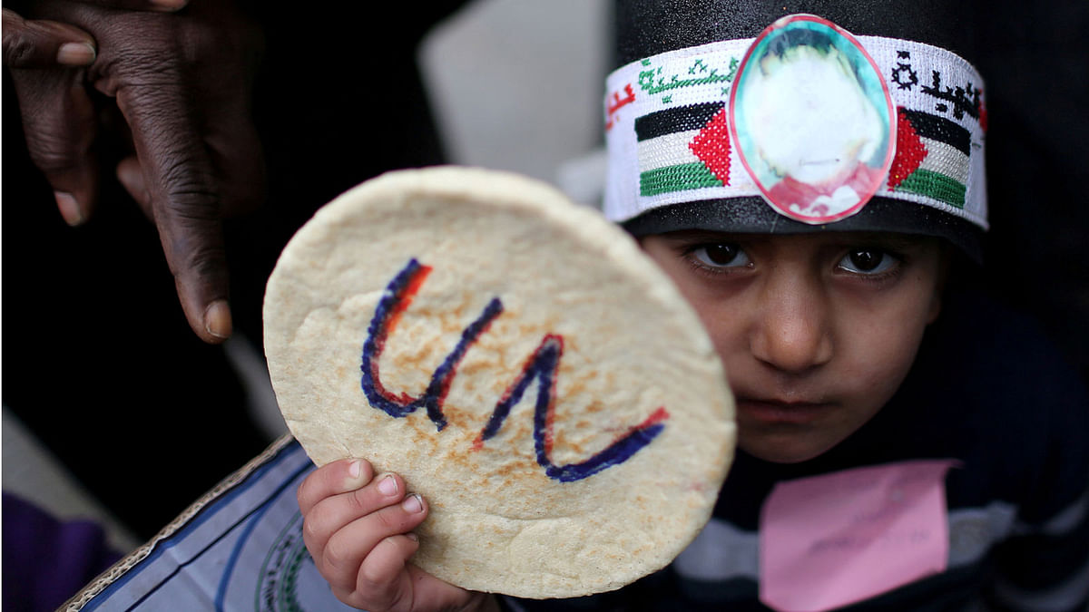 A Palestinian child holds bread during a protest against aid cuts, outside the United Nations’ offices in Khan Younis in the southern Gaza Strip on 28 January 2018. Photo: Reuters