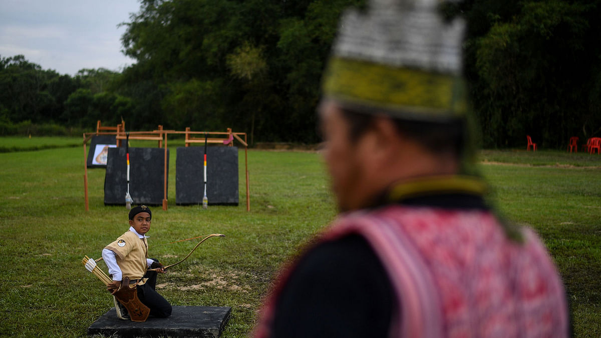 A young traditional archer (L) looks back before taking his aim during an International traditional archery festival at Seri Menanti in Negeri Sembilan, Malaysia about 90 kilometres of Kuala Lumpur on 28 January 2018. Photo: AFP