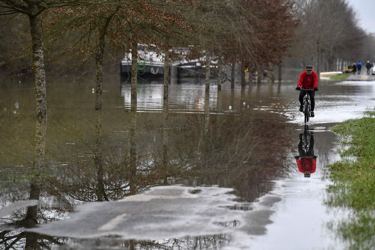 A man rides a bicycle on a flooded road on 29 January 2018 along the flooded banks of the Saone River between Tournus and Macon, eastern France. The Saone river was placed on 29 January in orange vigilance, part of a national phenomenon, caused by significant rainfall on soils full of water. December to January is recorded as one of the three rainiest since the beginning of surveys-taking in 1900, according to Meteo-France.  Photo: AFP