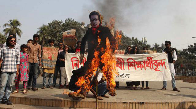 A section of students of Dhaka University under the banner ` Anti- harassment Students Forum` burns the effigy of proctor Golam Rabbani in front of Raju Sculpture on the campus on Tuesday. Photo: Prothom Alo