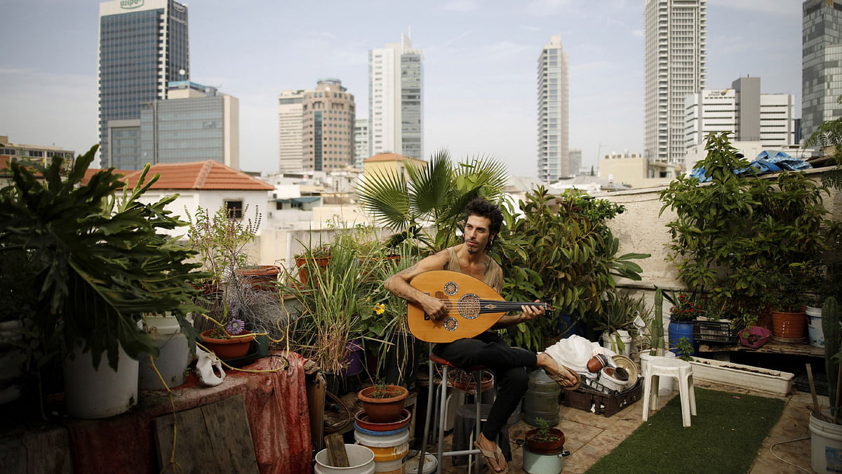 Musician Iyar Semel, 38, plays an oud on his rooftop garden, where he and his two other flatmates grow herbs and vegetables, in Tel Aviv, Israel, on 13 November 2017. Reuters