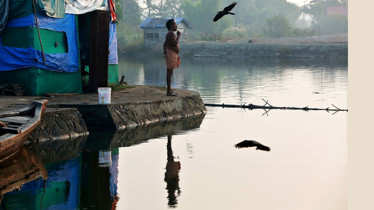A fisherman brushes his teeth as he stands outside a temporary shelter on the bank of Periyar River, on the outskirts of Kochi, India on 9 February. Photo: Reuters