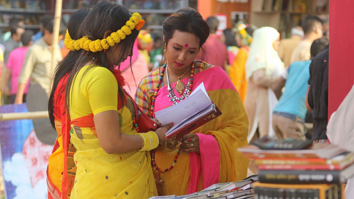 Book-lovers wearing traditional dresses browses through books on Tuesday, Pahela Falgun. Photo: Syful Islam