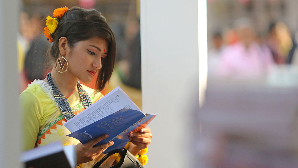 Clad in traditional dress, a bibliophile browses through the pages of a book on the premises of Ekushey book fair on Tuesday. Photo: Syful Islam