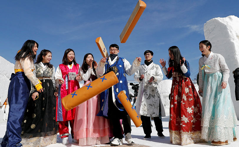People dressed in traditional Korean clothes play a game as they celebrate Lunar New Year among ice sculptures in Pyeongchang, South Korea, on 16 February 2018. Reuters