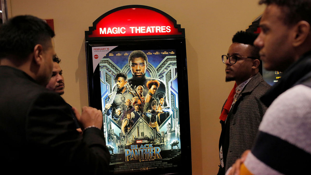 A group of men gather in front of a poster advertising the film `Black Panther` on its opening night of screenings at the AMC Magic Johnson Harlem 9 cinemas in Manhattan, New York, US, 15 February, 2018. Photo: Reuters