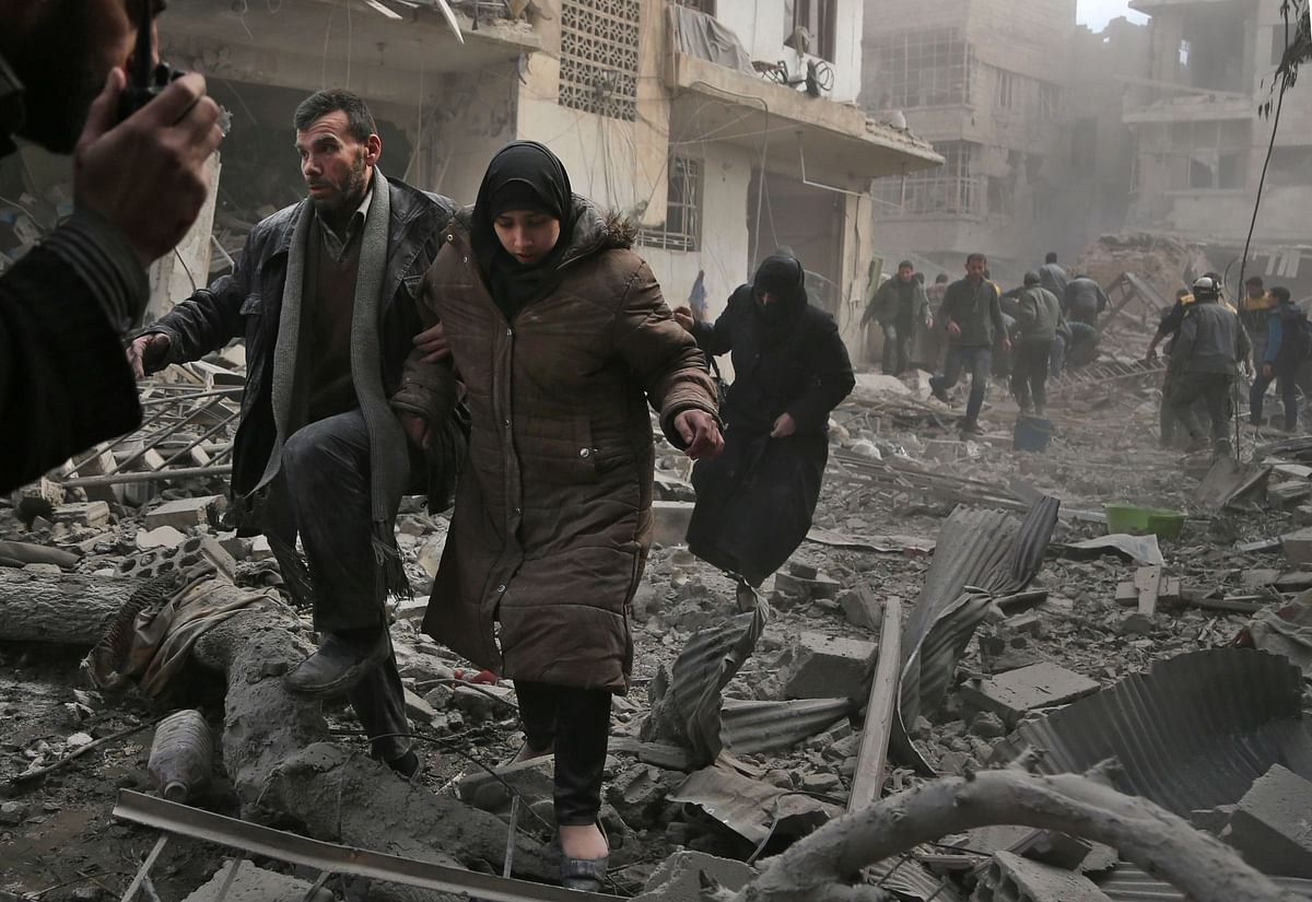 A member of the Syrian civil defence speaks on a wireless transmitter as other civilians flee from an area hit by a reported regime air strike in the rebel-held town of Saqba, in the besieged Eastern Ghouta region on the outskirts of the capital Damascus, on 20 February 2018. Photo: AFP