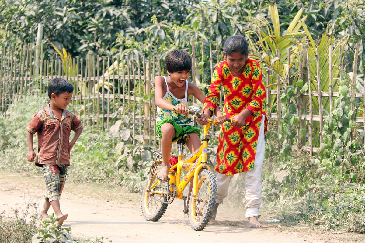 A young girl helps another girl ride a bicycle in Shyampur of Rangpur sadar upazila on 22 February. Photo: Mainul Islam