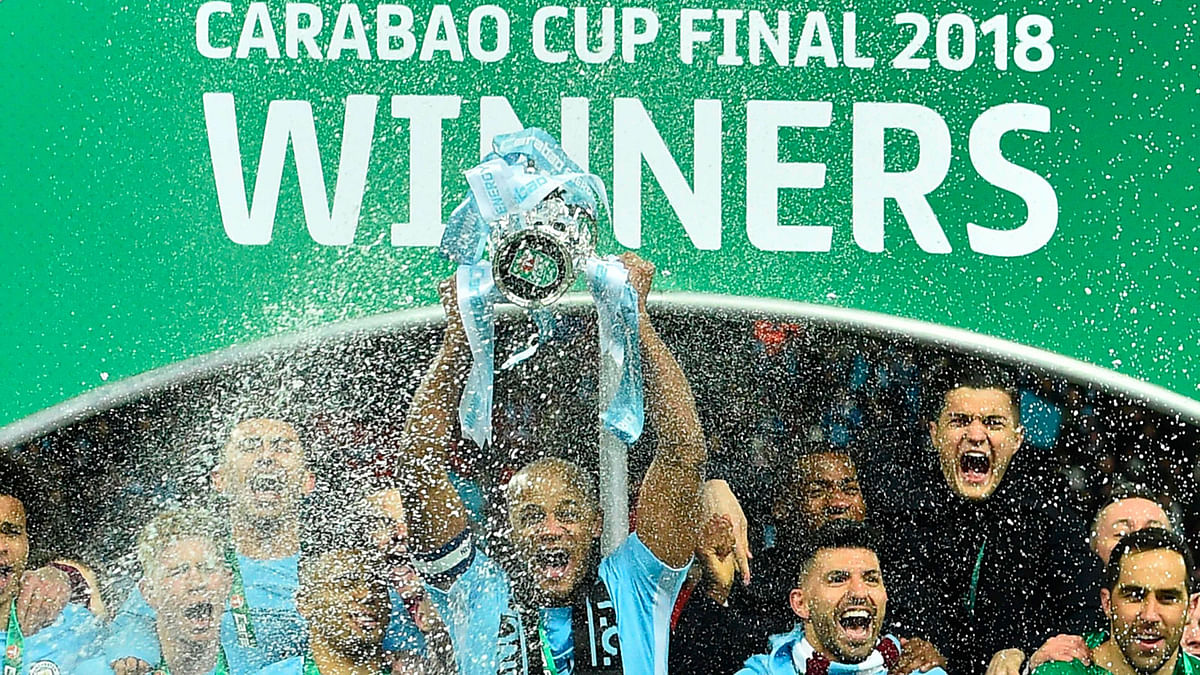 Manchester City’s Belgian defender Vincent Kompany lifts the trophy as Manchester city players celebrate their victory in the English League Cup final football match between Manchester City and Arsenal at Wembley stadium in north London on Sunday. Photo: AFP