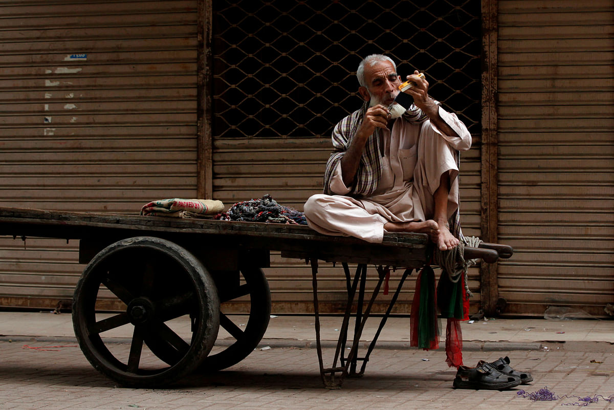 A labourer trims his moustaches while waiting for a work on his push-cart along a wholesale market in Karachi, Pakistan on 26 February. Photo: Reuters