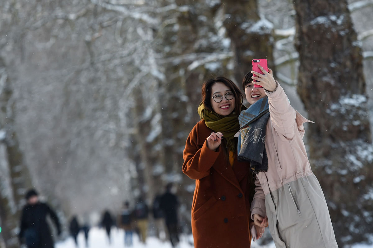 Two girls take photos in the snow in St James`s Park in London, Britain on 27 February. Photo: Reuters