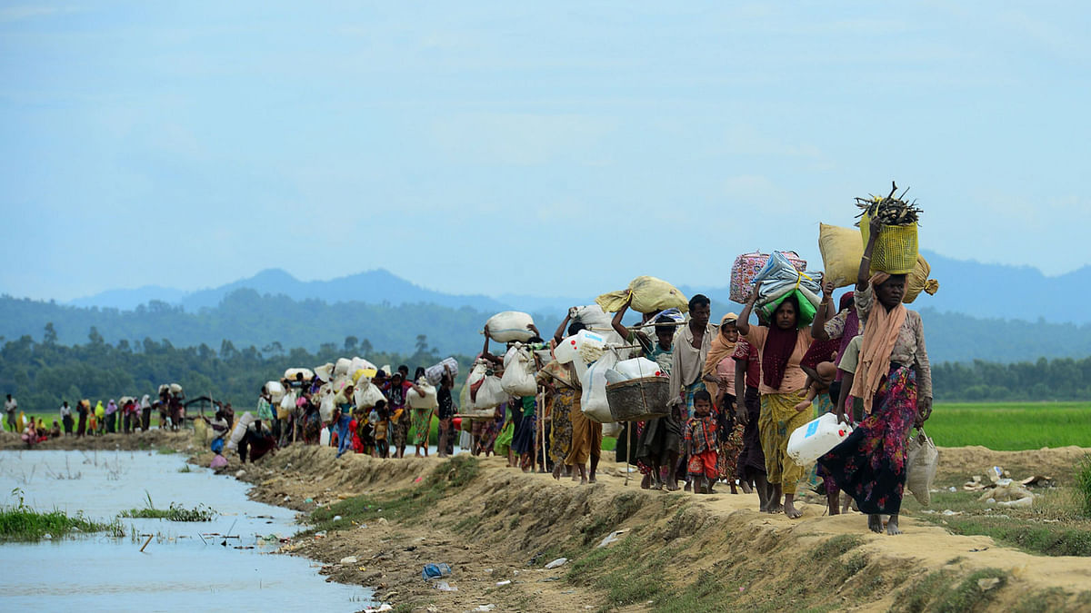 In this file photo taken on October 19, 2017 Rohingya refugees who were stranded walk near the no man`s land area between Bangladesh and Myanmar in the Palongkhali area next to Ukhia. Hundreds of desperate Rohingya Muslims still pour over the Myanmar border into Bangladesh camps every week, six months into the refugee crisis. AFP