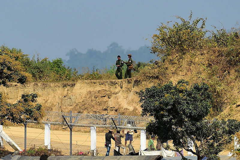 This photo taken on 27 February, 2018 shows Myanmar army personnel keeping watch as Myanmar workers build a fence along the Myanmar-Bangladesh border, as seen from Tombru in the Bangladeshi district of Bandarban. Photo: AFP