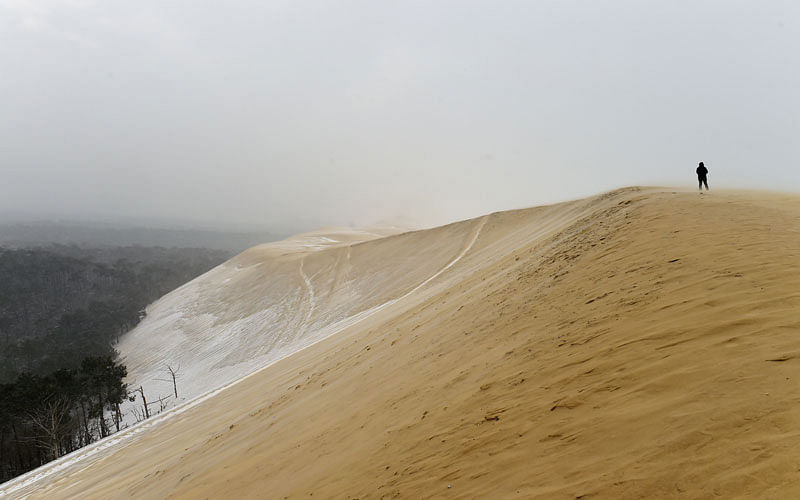 A man walks on the partially snow covered Pilat (or Pyla) sand dune after snow fall on February 28 in La Teste-de-Buch, southwestern France. Photo: AFP