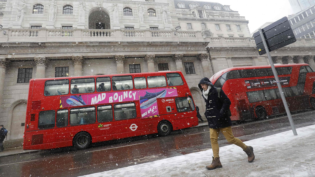 A red London bus makes it`s way through the snow as a blizzard hits central London on 2 March 2018. AFP