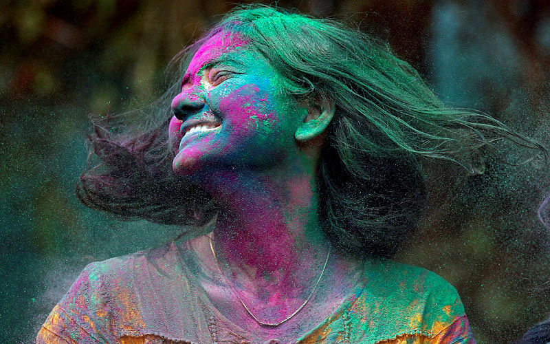 A woman smeared with coloured powder shakes her head to remove it during Holi celebrations in Mumbai, India on 2 March. Photo: Reuters