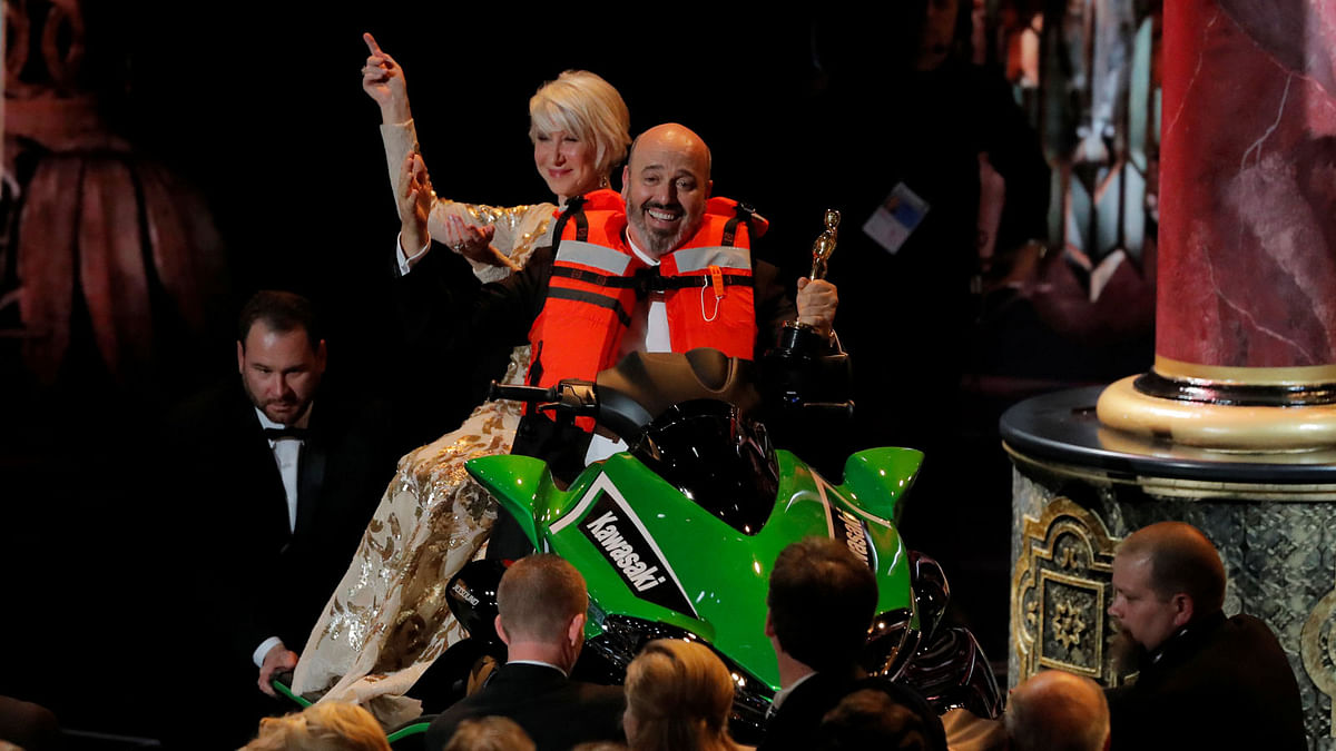Best Costume Design winner Mark Bridges rides a jet ski with actress Helen Mirren on the back after he won it for the shortest Oscar acceptance speech of 2018. Photo: Rueters